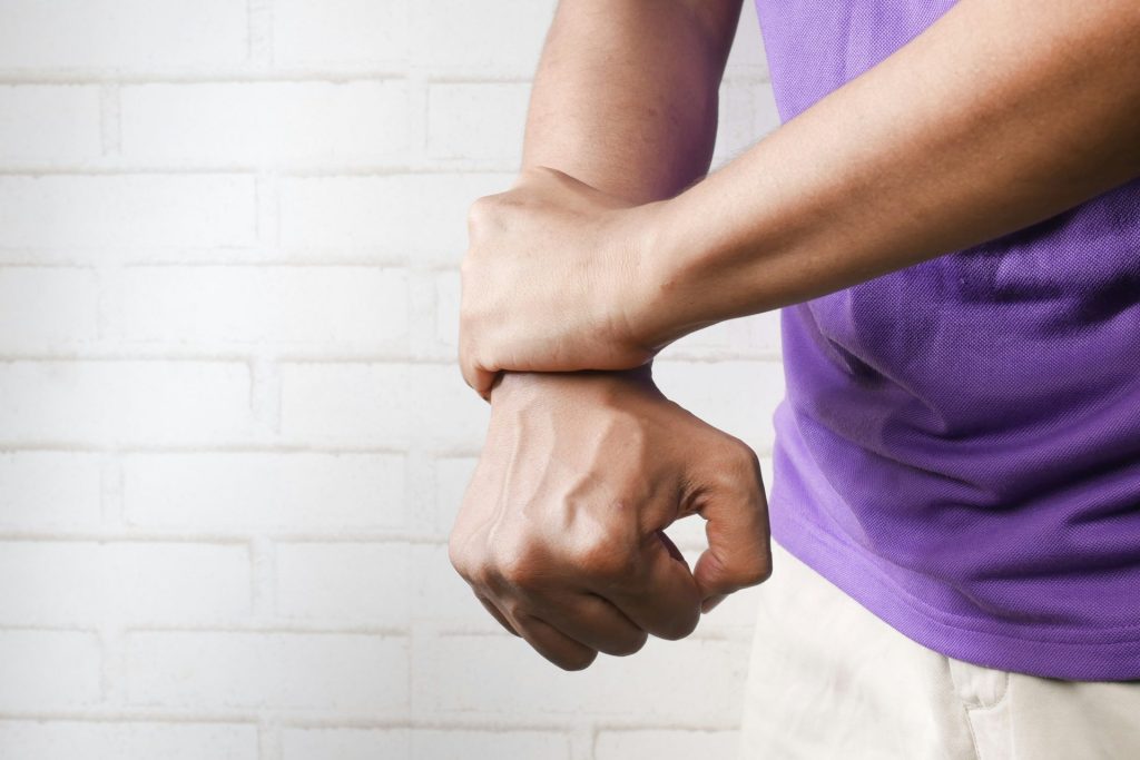 Man holding wrist in pain indoors.