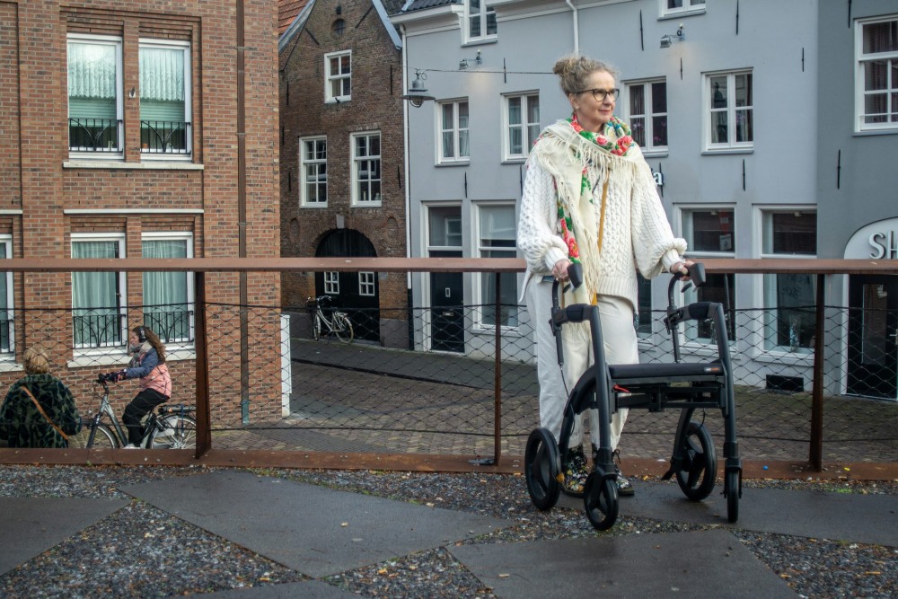 Elderly woman walking outside with rollator.